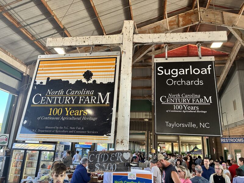 Sugarloaf Orchards and Century Farm signs hang above a busy market aisle.