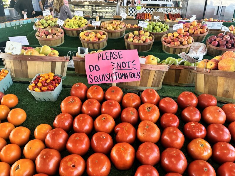 Tomatoes and baskets of produce, with a handwritten request not to squeeze the fruit.