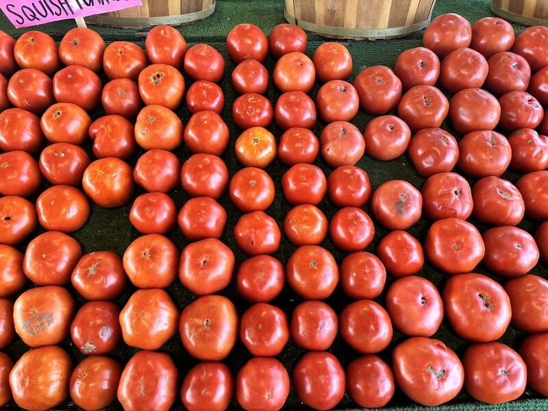 Rows of red tomatoes fill a produce display.