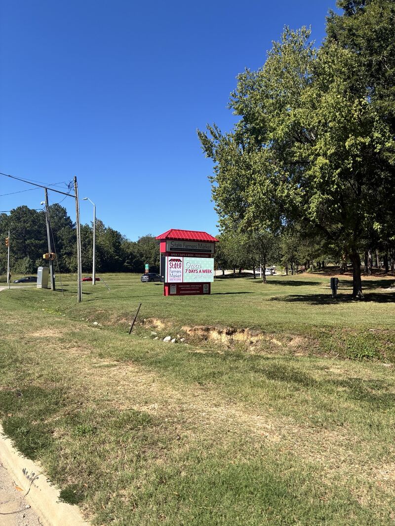 A roadside sign beside the market approach.