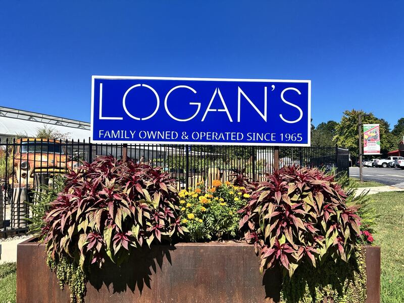 The Logan’s sign rises above foliage.