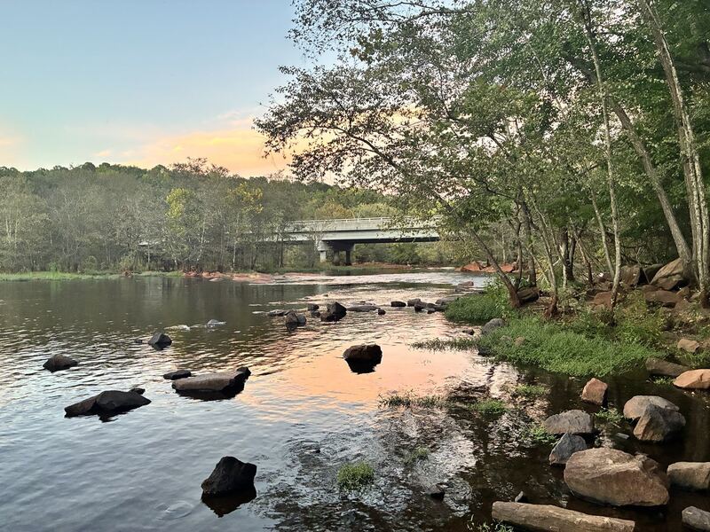 The Neuse below the dam: wooded banks, exposed rocks and the evening reflected in the water.