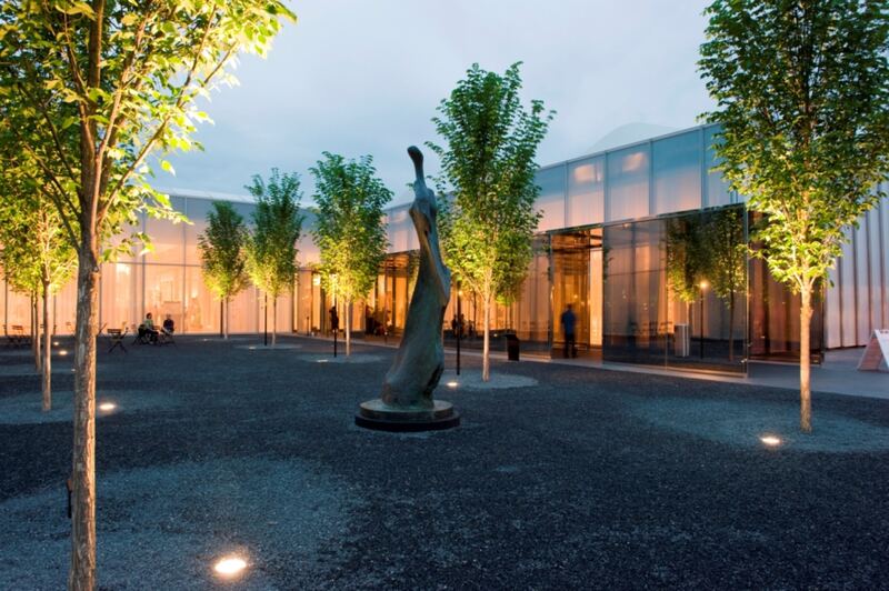 Exterior of West Building entrance and courtyard garden at night — North Carolina Museum of Art.
